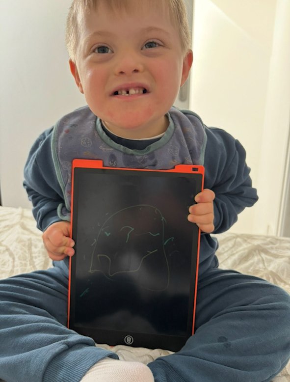 A young boy proudly showing his artwork on an electronic drawing tablet