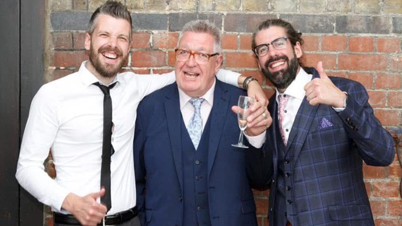 Three men in suits smiling
