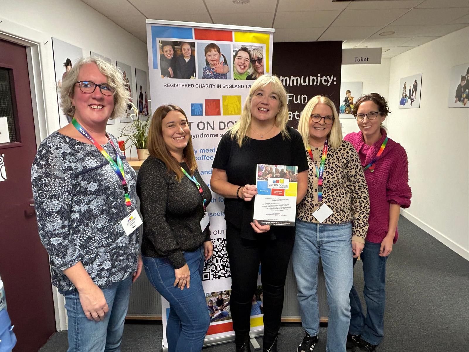 Five members of the Get On Downs trustee team standing together in front of a charity banner