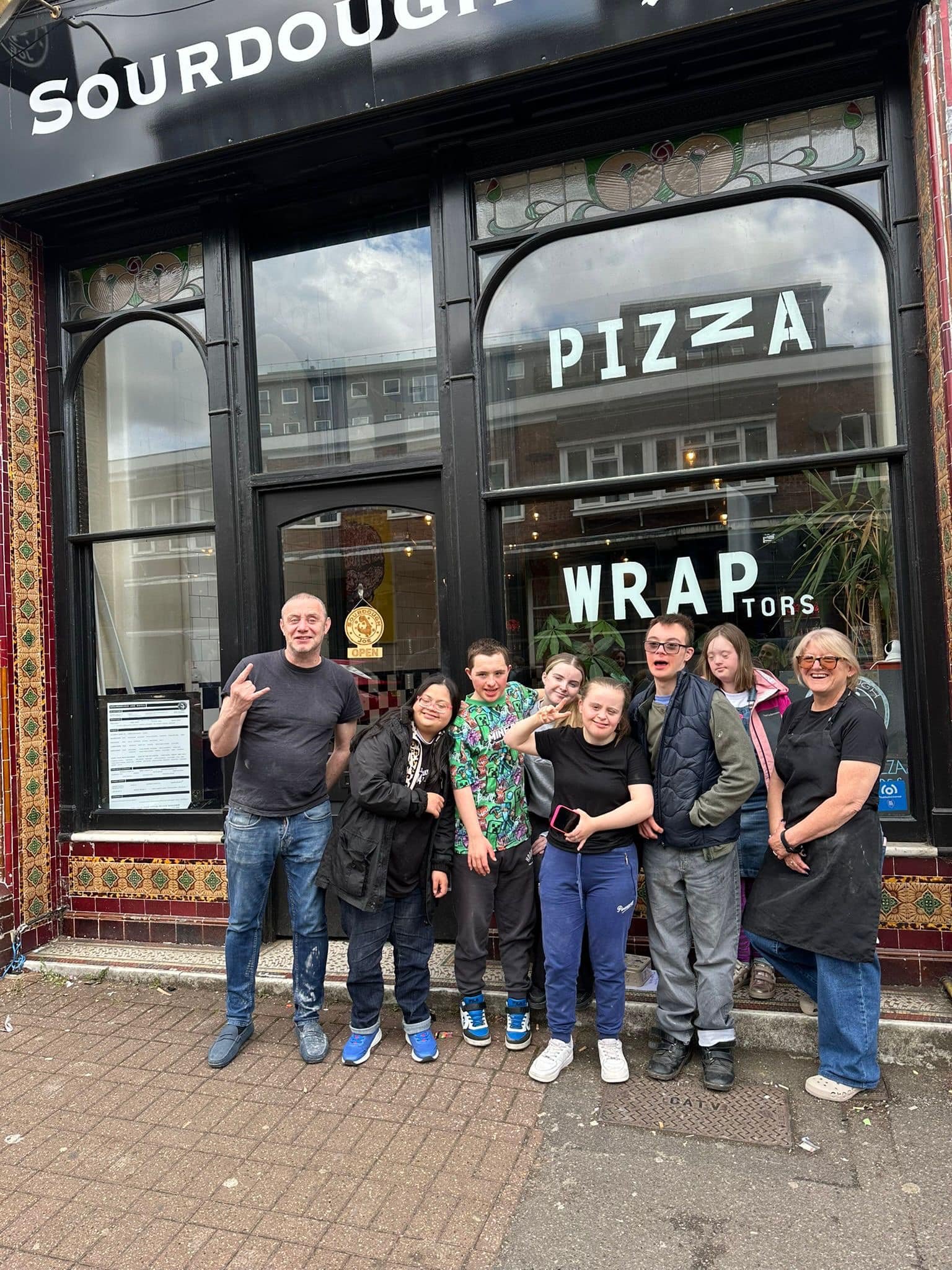 A mix group of teenagers outside pizza restaurant