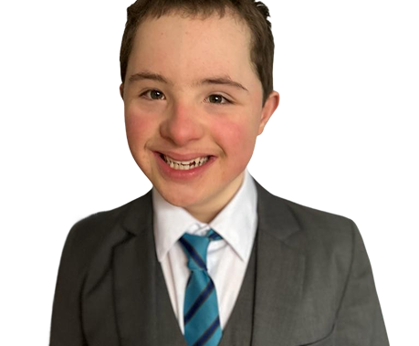 A teenage boy in a smart grey suit and blue tie smiling confidently