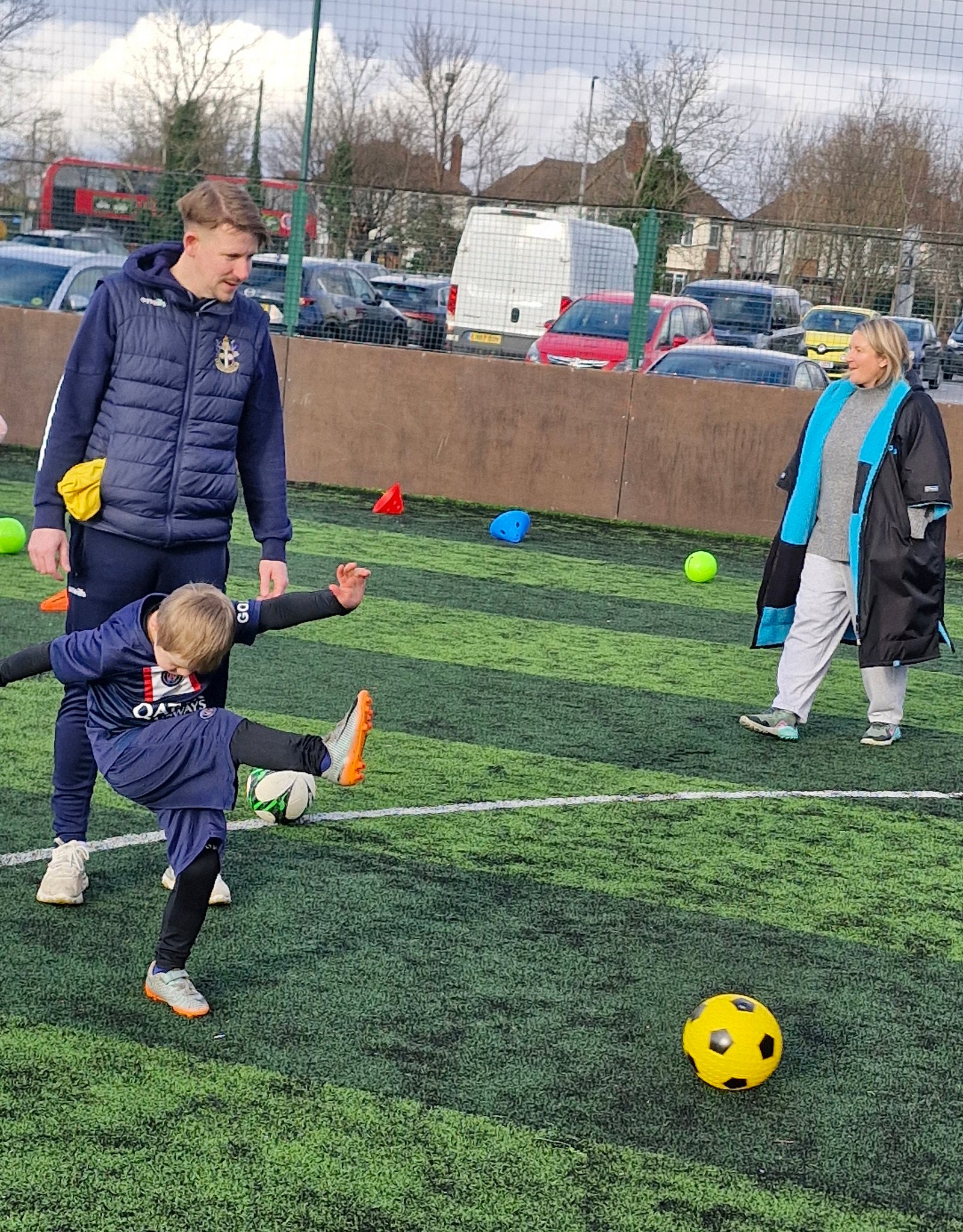 A young boy in a football kit kicking a ball at a Sutton United coaching session